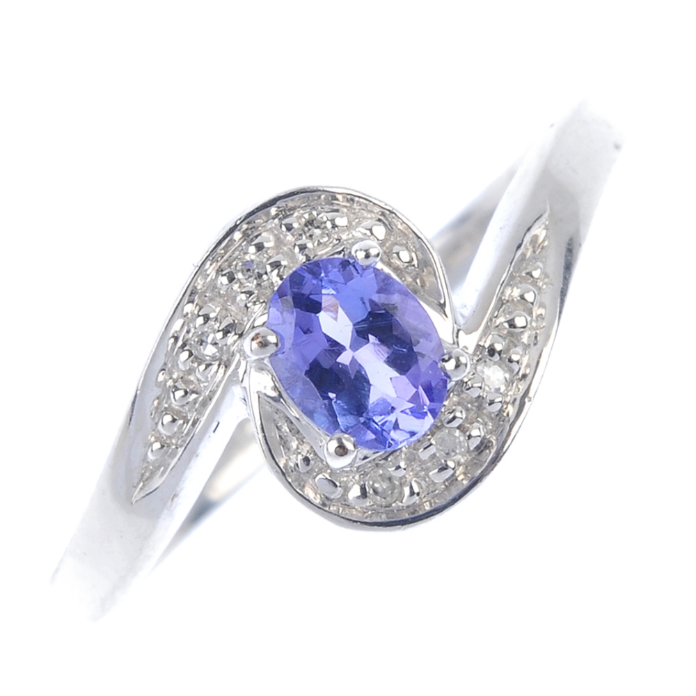 A 9ct gold tanzanite and diamond crossover ring. The oval-shape tanzanite, to the pave-set single-