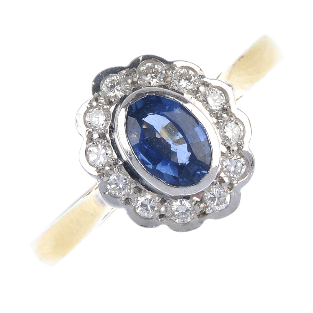 An 18ct gold sapphire and diamond cluster ring. The oval-shape sapphire collet, within a brilliant-