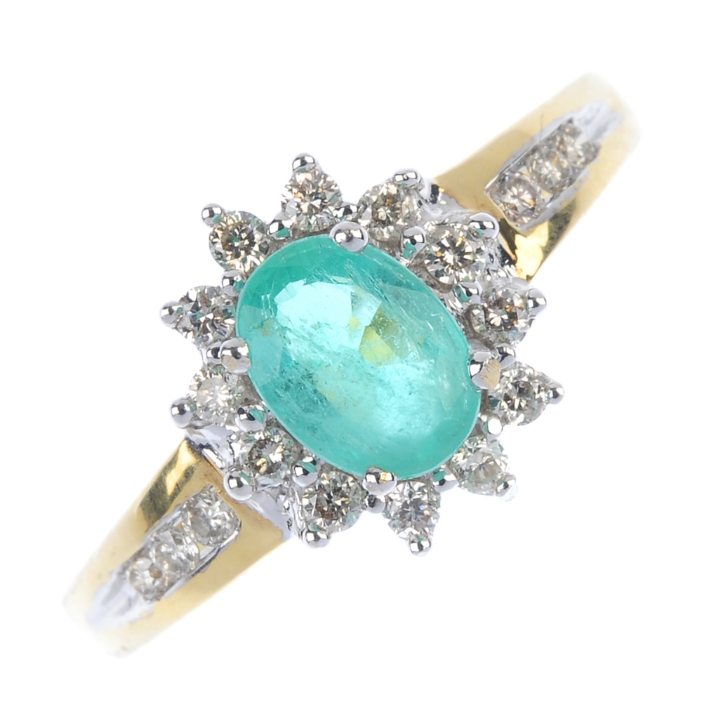 * An 18ct gold emerald and diamond cluster ring. The oval-shape emerald, within a brilliant-cut