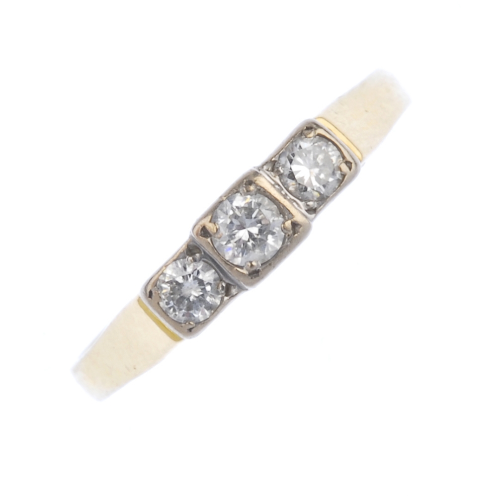 An 18ct gold diamond three-stone ring. The brilliant-cut diamond stepped line, to the tapered
