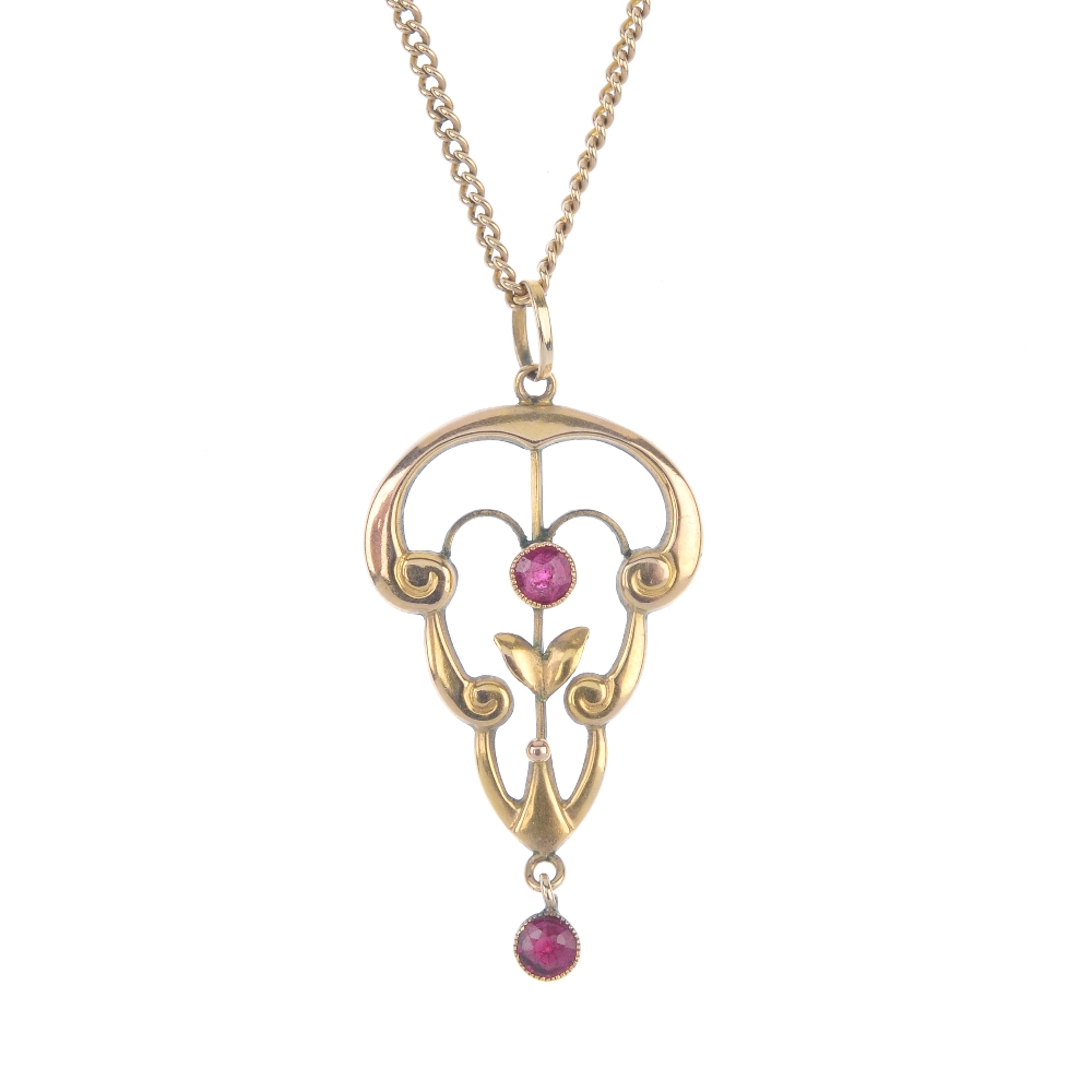 An early 20th century 9ct gold garnet-topped-doublet pendant. Of scrolling openwork design, set with