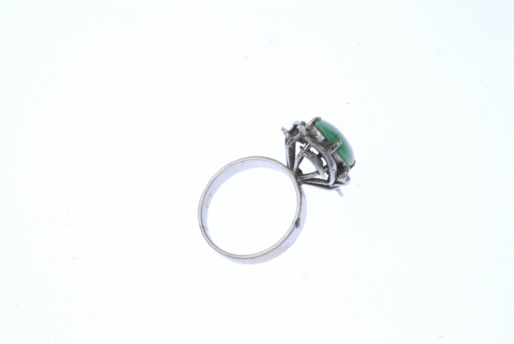 A jadeite dress ring. The oval jadeite cabochon, within a foliate surround, to the plain band. - Image 4 of 4