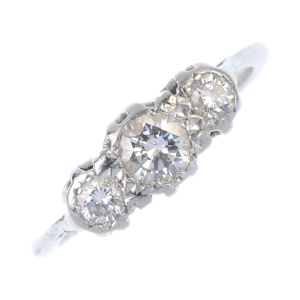 A mid 20th century diamond three-stone ring. The graduated brilliant-cut diamond line, to the