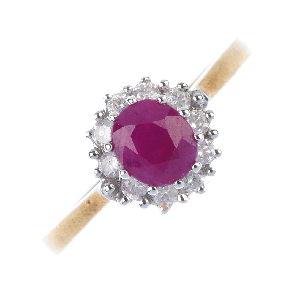 A 9ct gold ruby and diamond cluster ring. The oval-shape ruby, within a brilliant-cut diamond