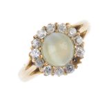 A cat's-eye chrysoberyl and diamond cluster ring. The circular cat's-eye chrysoberyl cabochon,