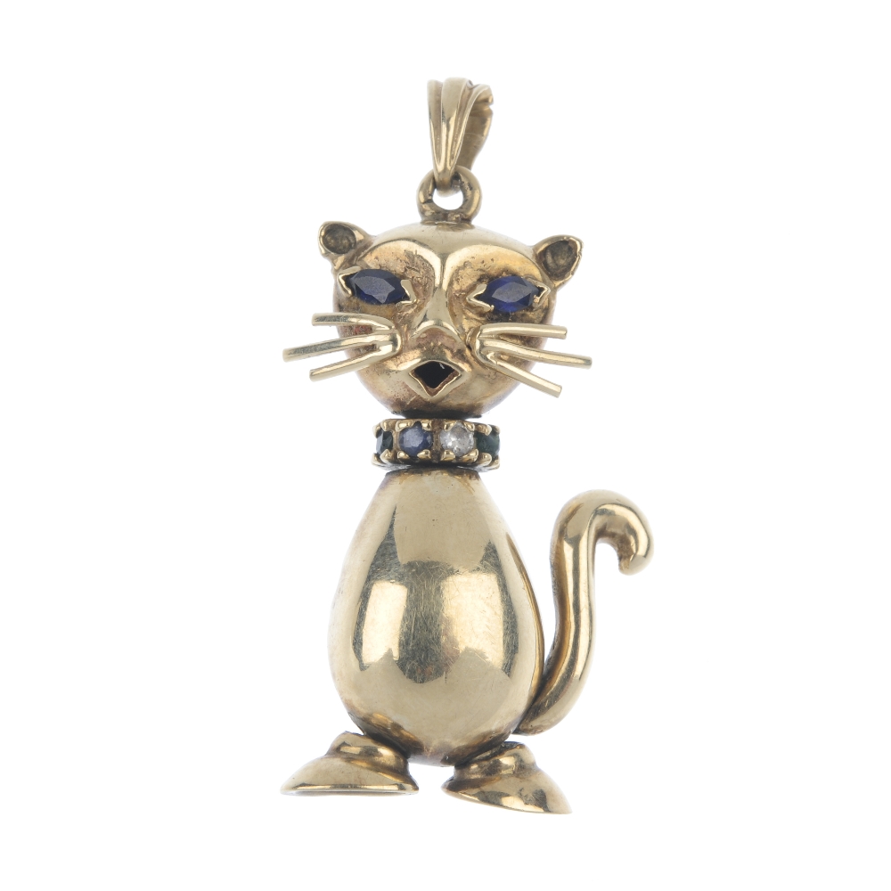 A 9ct gold gem-set novelty pendant. Designed as a cat, with synthetic sapphire eyes and vari-gem