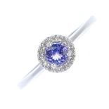 A 9ct gold tanzanite and diamond cluster ring. The circular-shape tanzanite, within single-cut