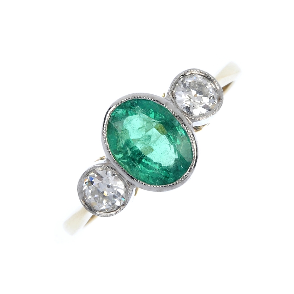 An emerald and diamond three-stone ring. The oval-shape emerald, with old-cut diamond shoulders.