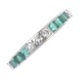 A mid 20th century platinum emerald and diamond full-circle eternity ring. Set with a series of