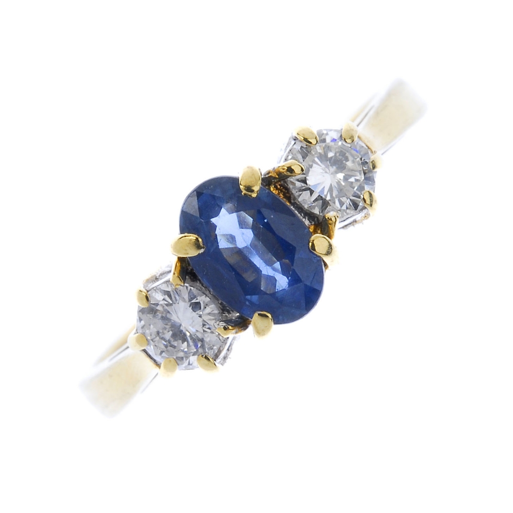 An 18ct gold sapphire and diamond three-stone ring. The oval-shape sapphire. between brilliant-cut