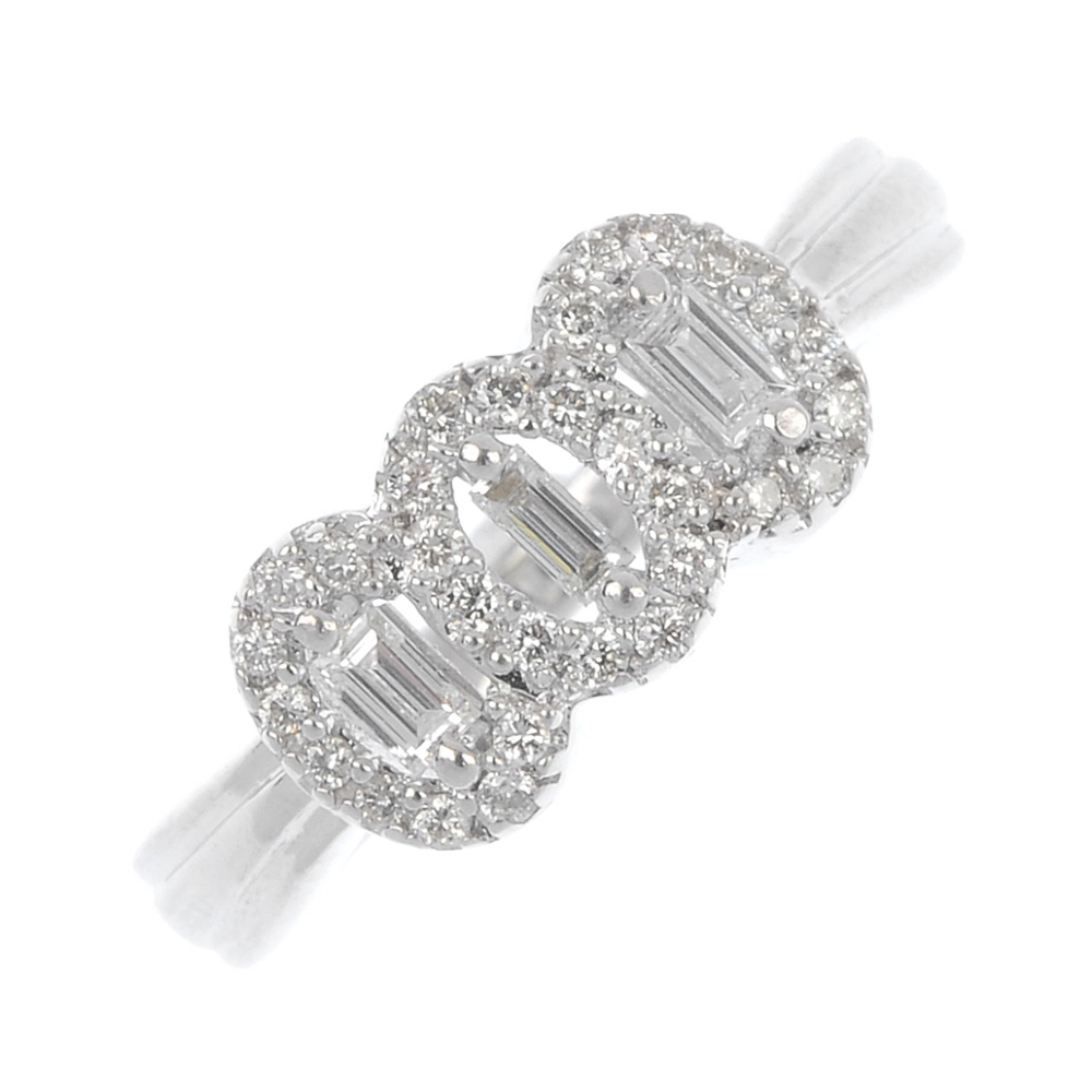 An 18ct gold diamond cluster ring. Comprising thee baguette-cut diamonds, within a brilliant-cut