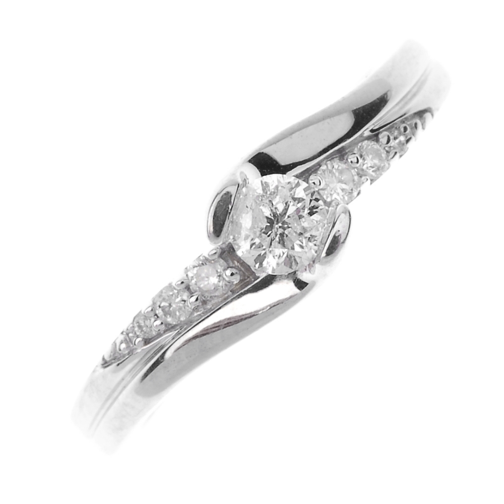 A diamond single-stone ring. The brilliant-cut diamond, to the similarly-cut diamond sides.