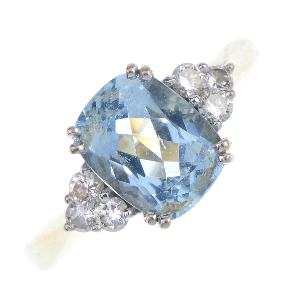 An 18ct gold aquamarine and diamond dress ring. The cushion-shape aquamarine, with brilliant-cut