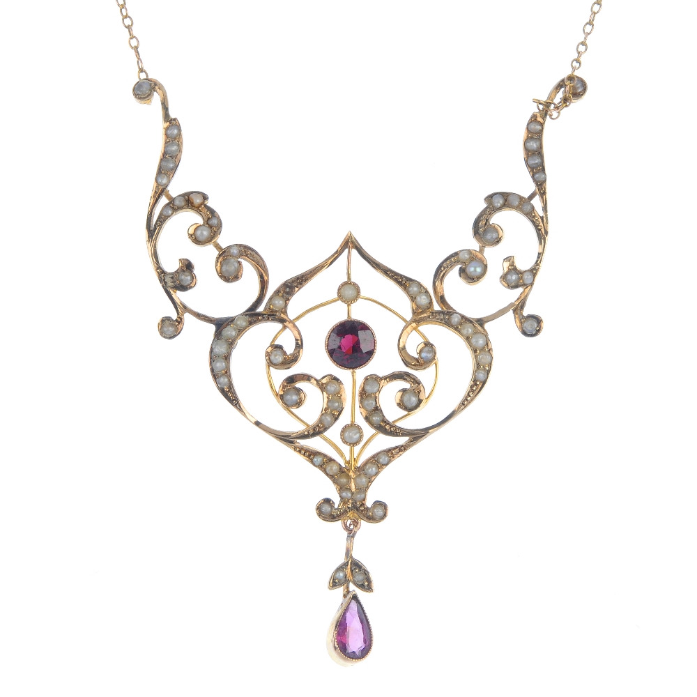 An early 20th century 9ct gold, garnet and split pearl necklace. Of openwork design, the circular-