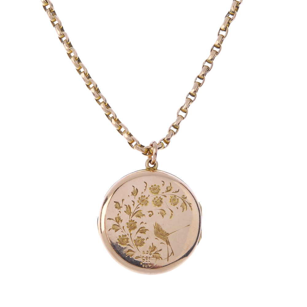 An early 20th century locket. Of circular outline, with engraved foliate motif, suspended from a