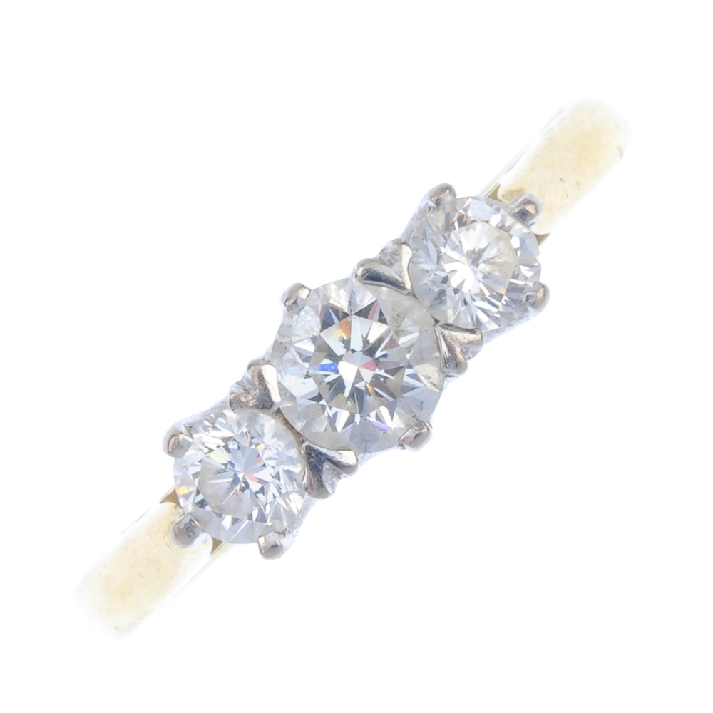 An 18ct gold diamond three-stone ring. The graduated brilliant-cut diamond line, to the plain