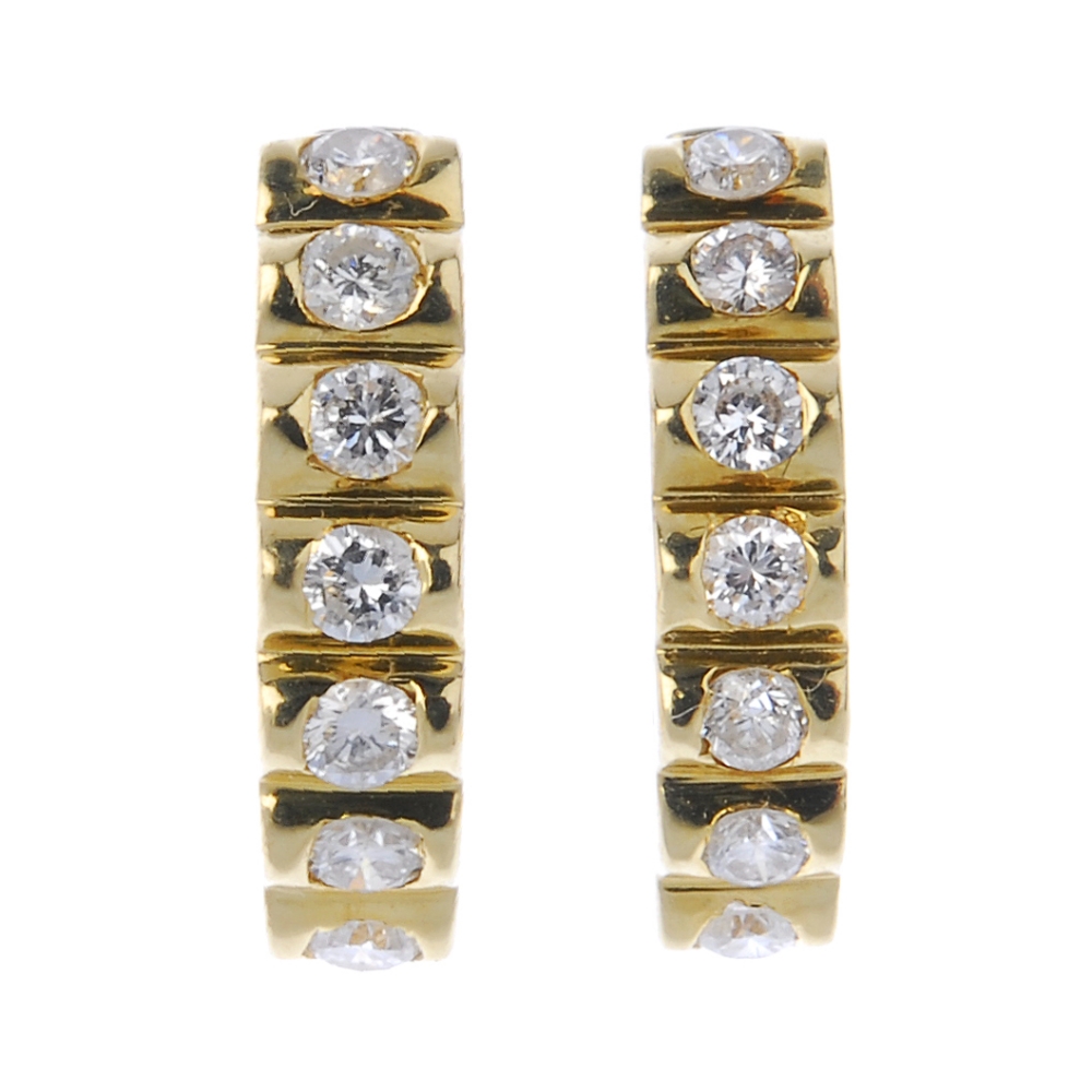 A pair of diamond ear hoops. Each designed as a brilliant-cut diamond line, to the plain half-hoop