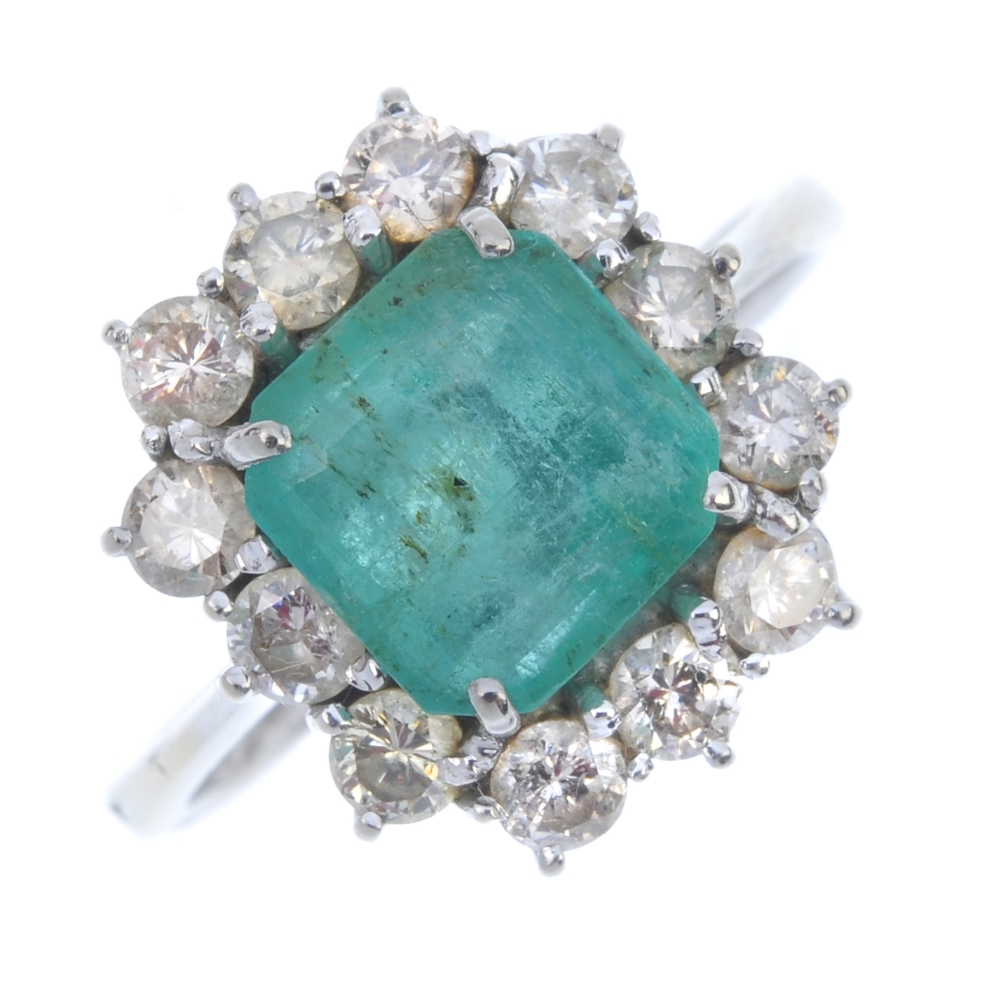An emerald and diamond cluster ring. The square-shape emerald, within a brilliant-cut diamond