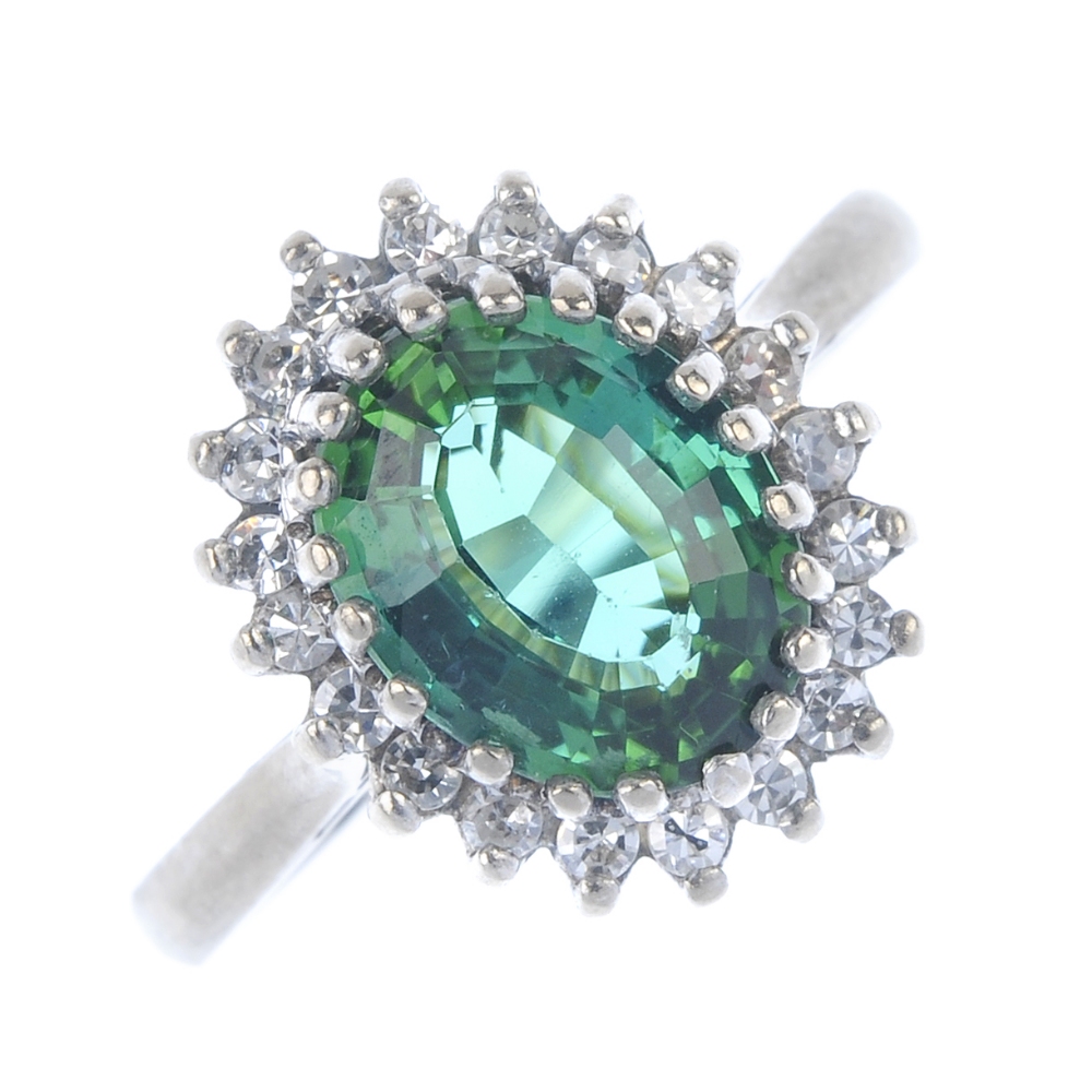 A tourmaline and diamond cluster ring. The oval-shape green tourmaline, within a single-cut