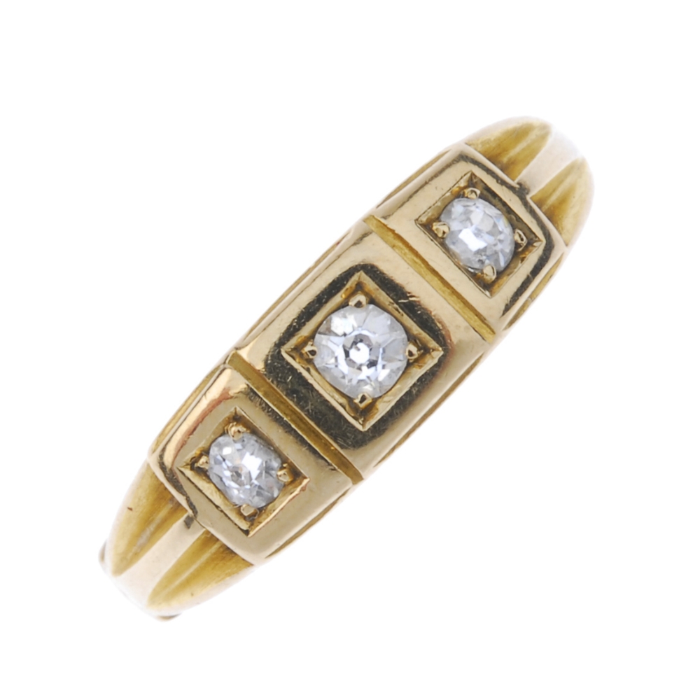 A late Victorian 18ct gold diamond three-stone ring. The graduated old-cut diamond line, to the