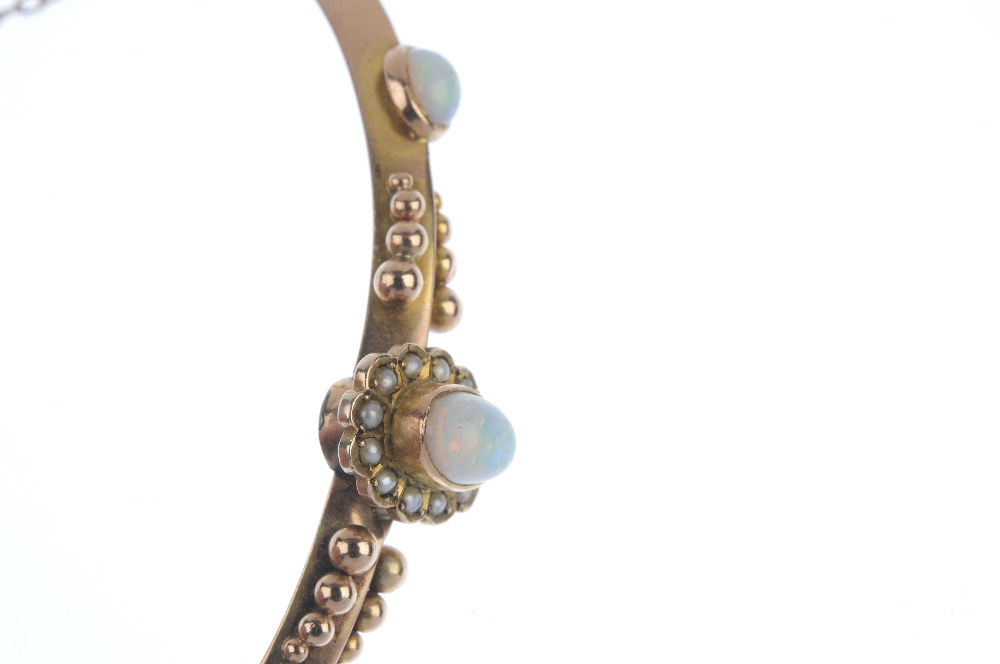 A late Victorian 9ct gold opal and split pearl hinged bangle. The oval opal cabochon and split pearl - Image 2 of 3