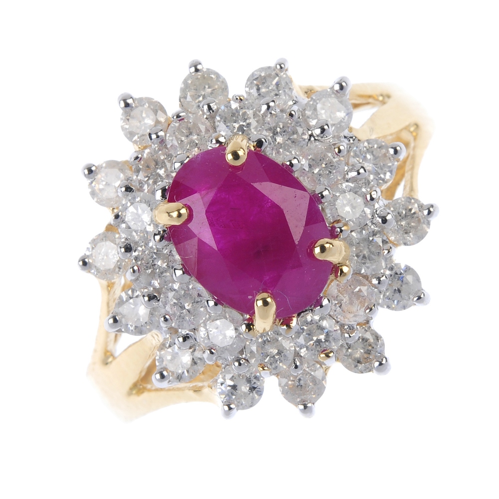 An 18ct gold ruby and diamond cluster ring. The oval-shape ruby, within a brilliant-cut diamond