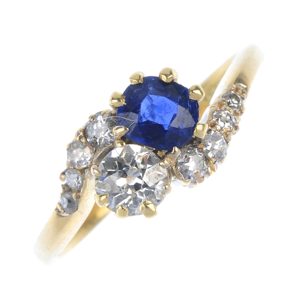 An early 20th century 18ct gold sapphire and diamond two-stone crossover ring. The cushion-shape