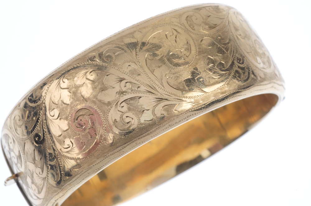 A mid 20th century 9ct gold hinged bangle. The hollow bangle, with foliate and scroll motif, to - Image 2 of 3
