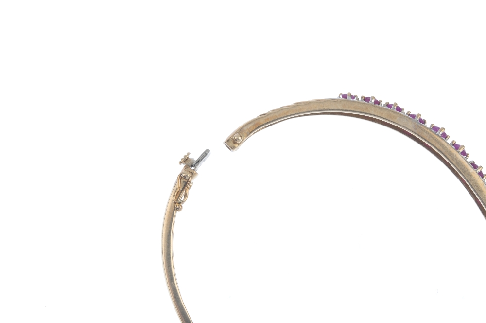 A ruby and diamond hinged bangle. Designed as a slightly graduated circular-shape ruby line, with - Image 3 of 3
