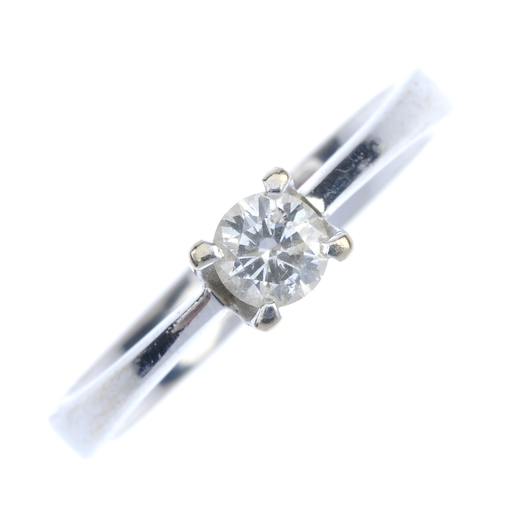 A diamond single-stone ring. The brilliant-cut diamond, to the tapered shoulders and plain band.