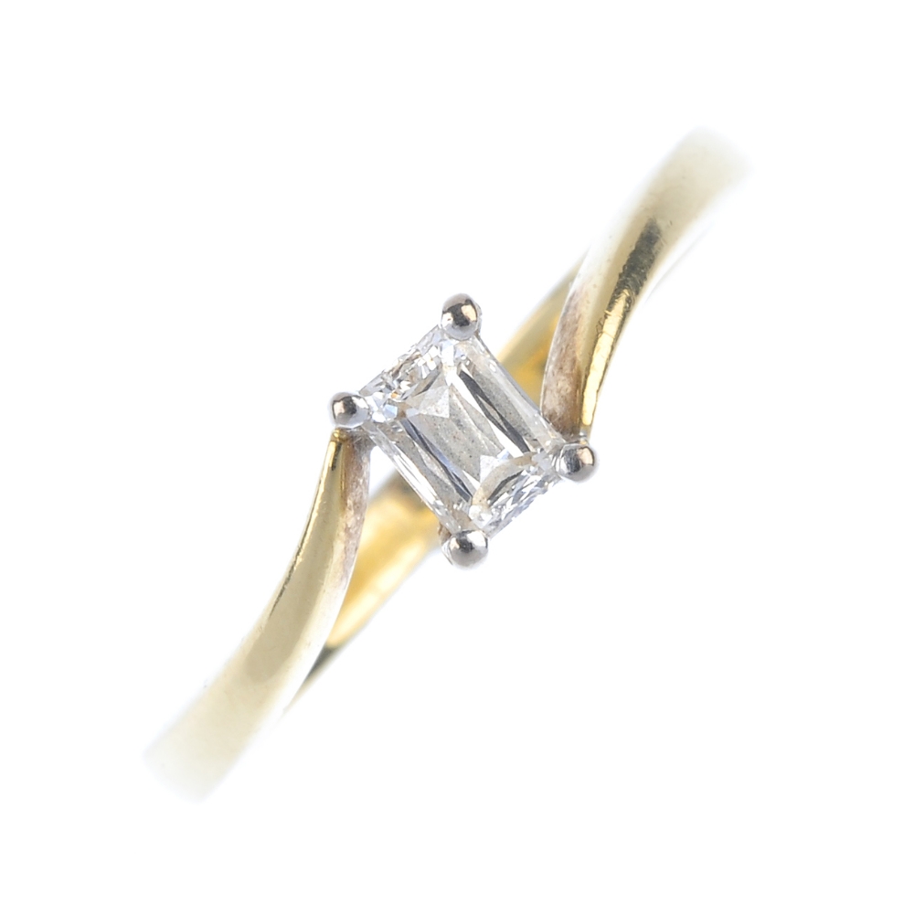 An 18ct gold diamond single-stone ring. The rectangular-shape diamond, to the asymmetric shoulders