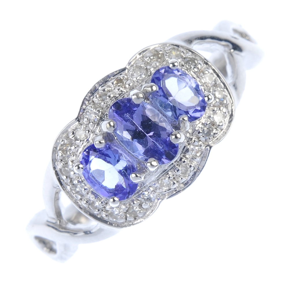 A 9ct gold tanzanite and diamond dress ring. The graduated oval-shape tanzanite line, within a