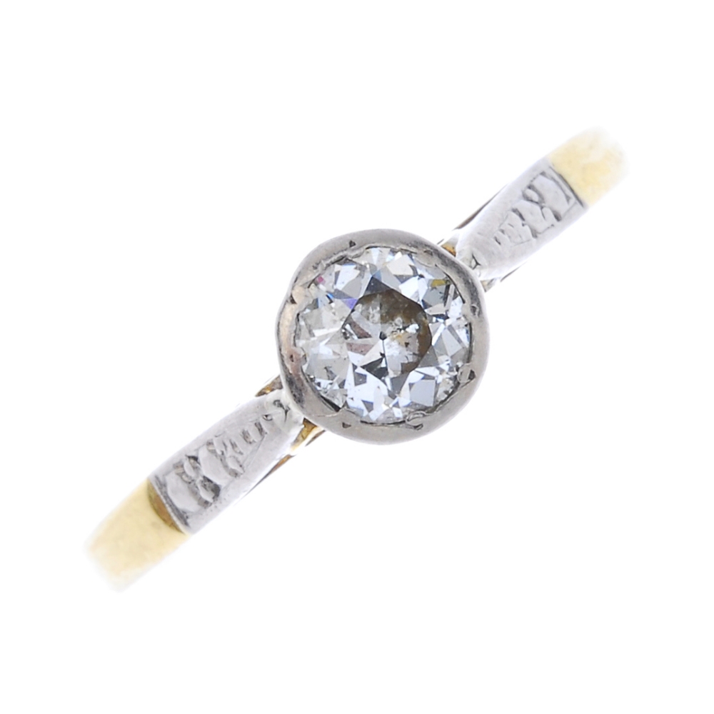 An 18ct gold diamond single-stone ring. The circular-cut diamond, to the foliate engraved