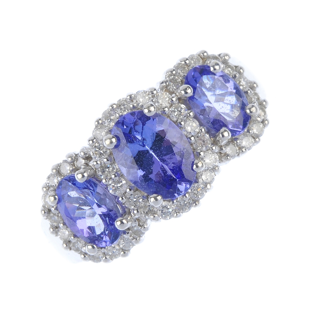 An 18ct gold tanzanite and diamond triple cluster ring. The slightly graduated oval-shape