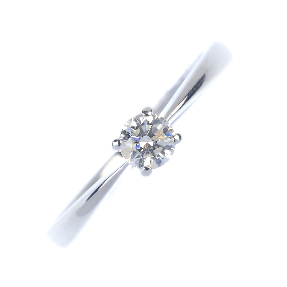 An 18ct gold diamond single-stone ring. The brilliant-cut diamond, to the tapered shoulders and