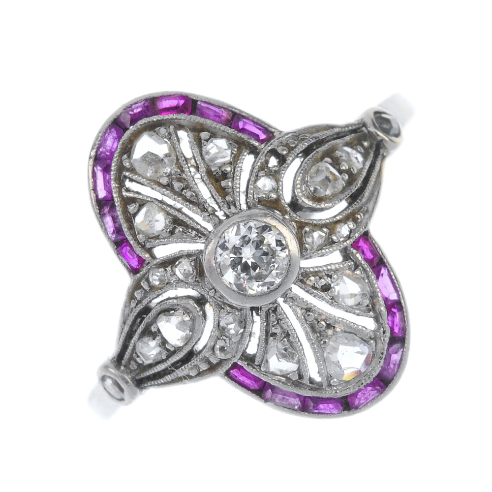 A diamond and ruby dress ring. The circular-cut diamond collet, within a rose-cut diamond pierced