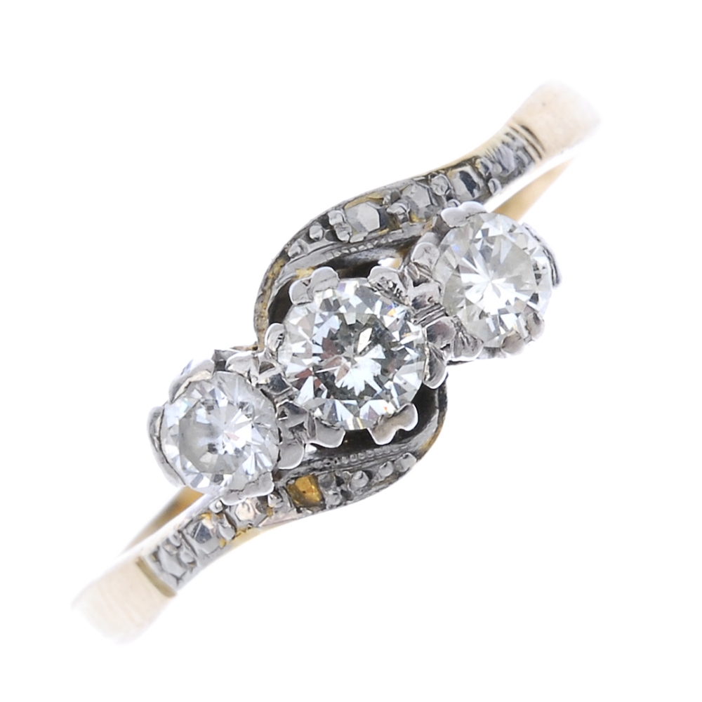 A diamond three-stone crossover ring. The graduated brilliant-cut diamond diagonal line, to the