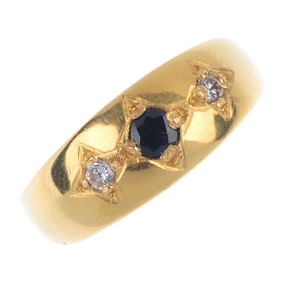 A diamond and sapphire band ring. The circular-shape sapphire and brilliant-cut diamond sides,