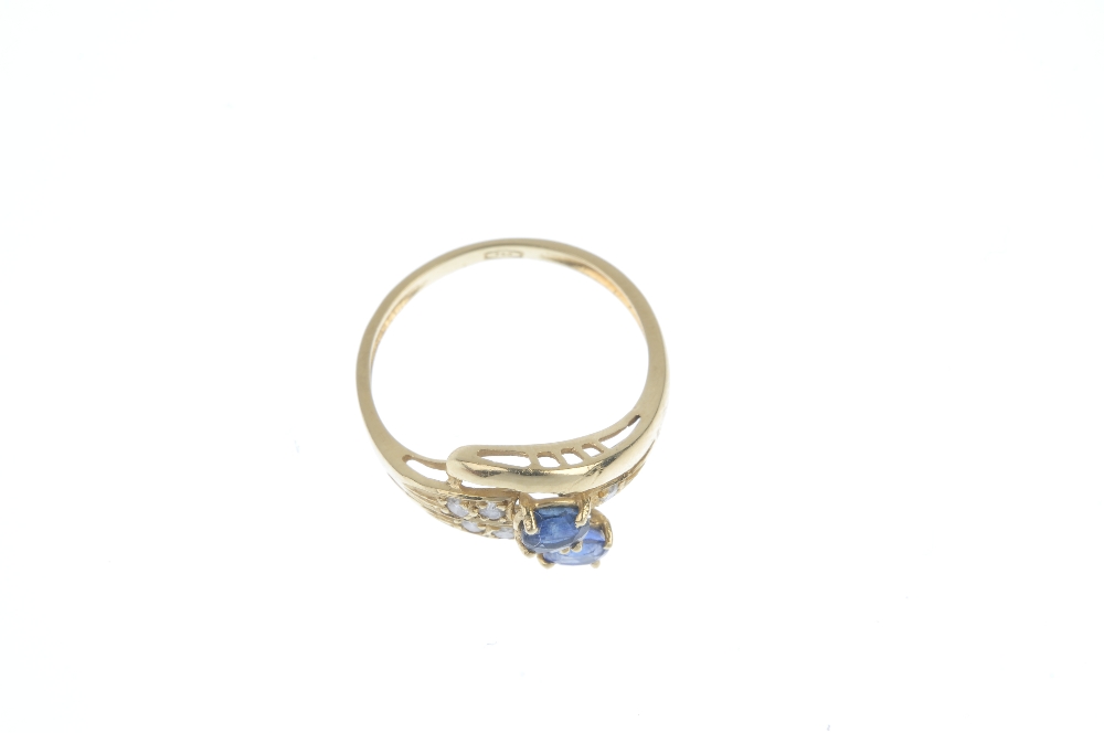 A sapphire and diamond dress ring. The oval-shape sapphire and brilliant-cut diamond scrolling band, - Image 2 of 3