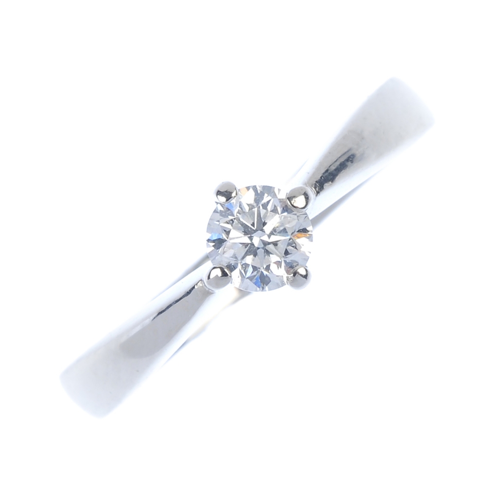 A platinum diamond single-stone ring. The brilliant-cut diamond, to the tapered shoulders and
