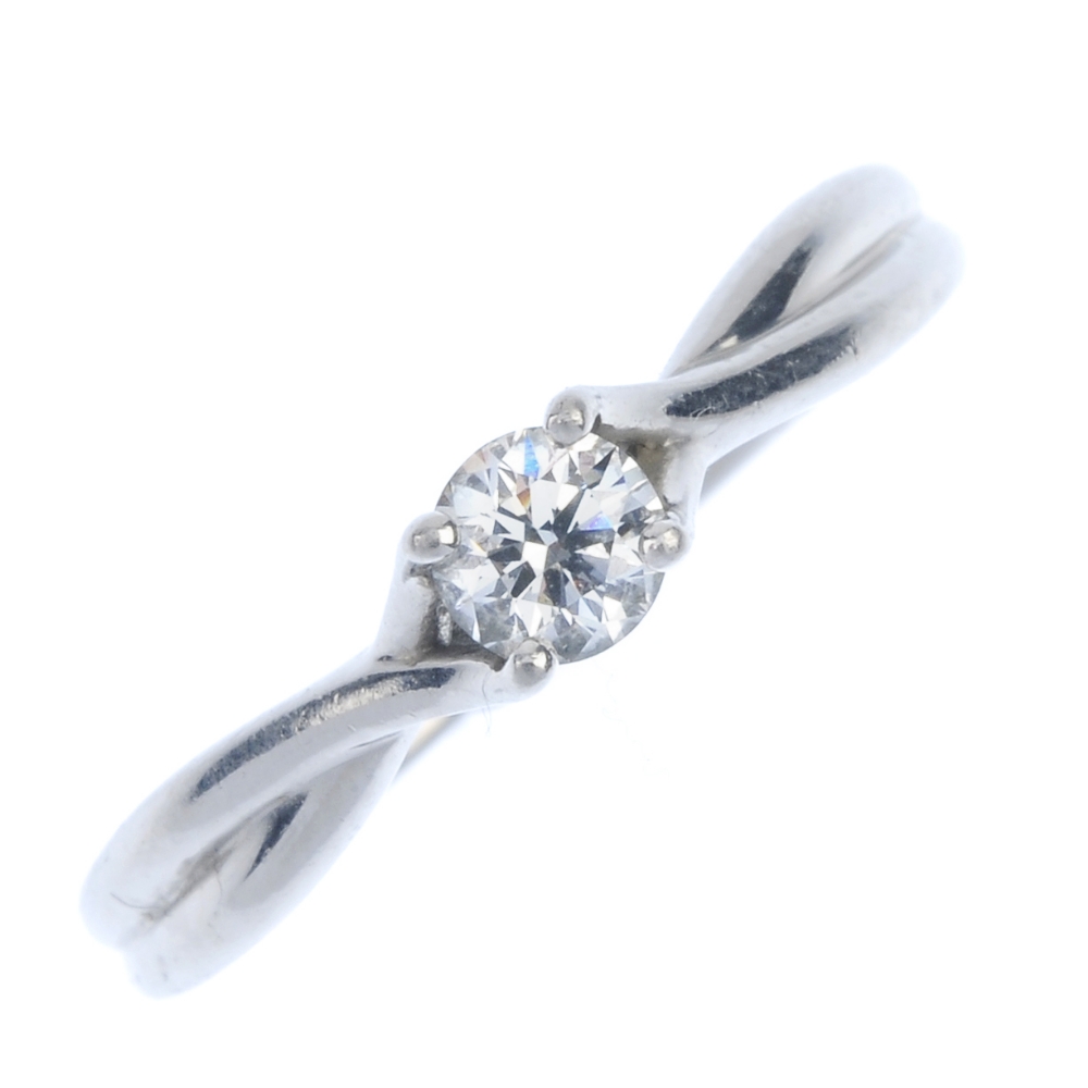 A platinum diamond single-stone ring. The brilliant-cut diamond, to the crossover shoulders and