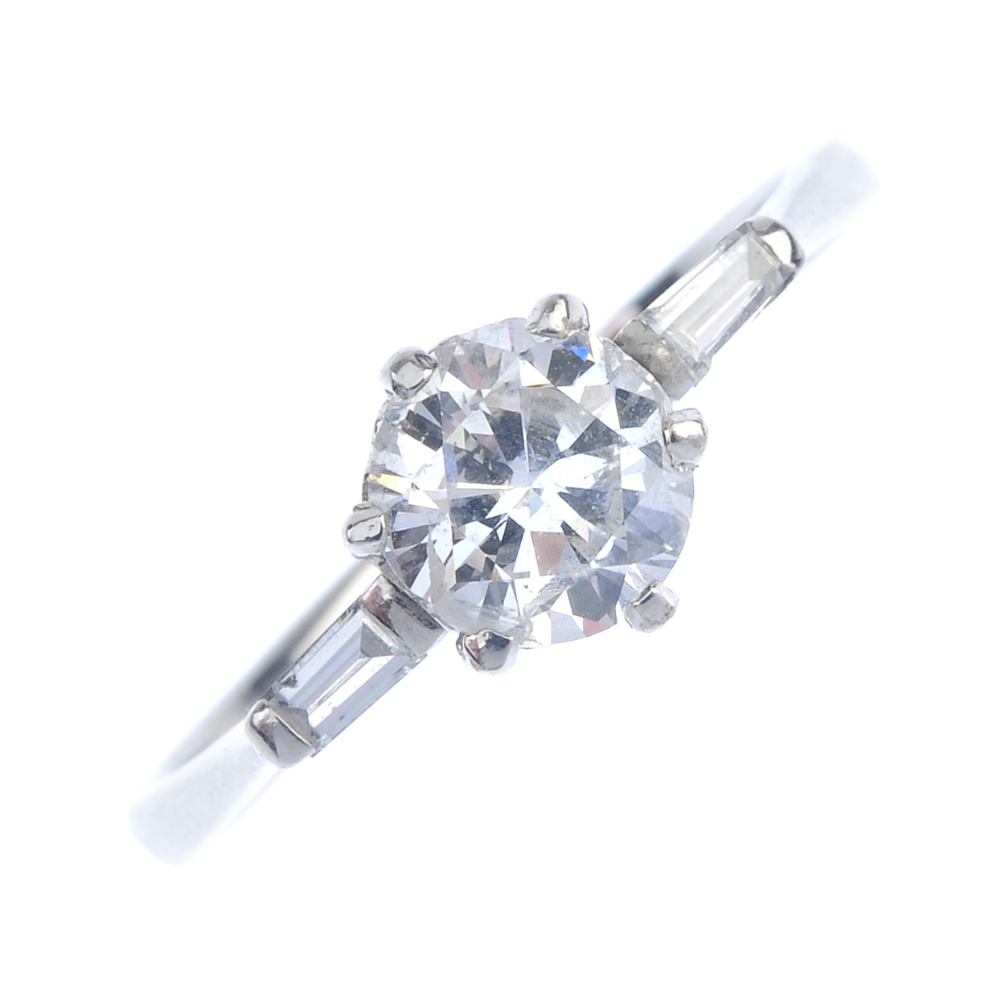 An 18ct gold diamond single-stone ring. The brilliant-cut diamond, to the tapered baguette-cut