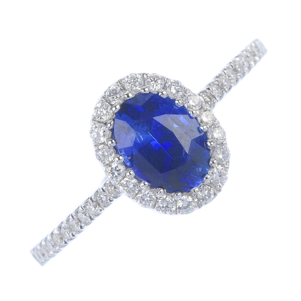 * An 18ct gold sapphire and diamond cluster ring. The oval-shape sapphire, within a brilliant-cut