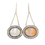 Two shell cameo ear pendants. Each designed as an oval-shape shell cameo, within a seed pearl and