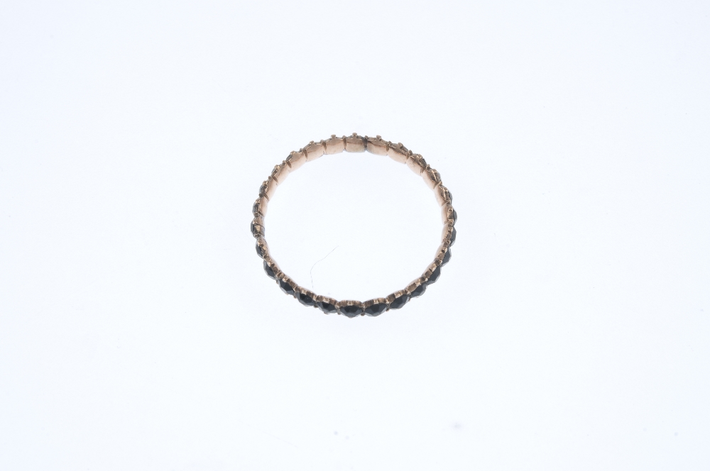 A late 19th century 9ct gold garnet full-circle eternity ring. Comprising a circular-shape black - Image 3 of 3