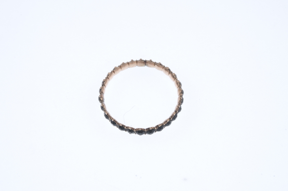 A late 19th century 9ct gold garnet full-circle eternity ring. Comprising a circular-shape black - Image 2 of 3