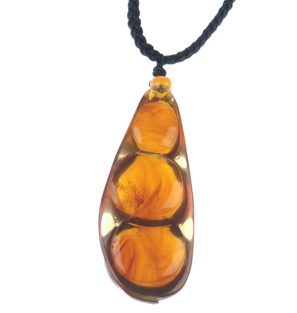 A natural Burmese amber pendant carved as a pea pod. The plaited black cord suspending the pear- - Image 2 of 3