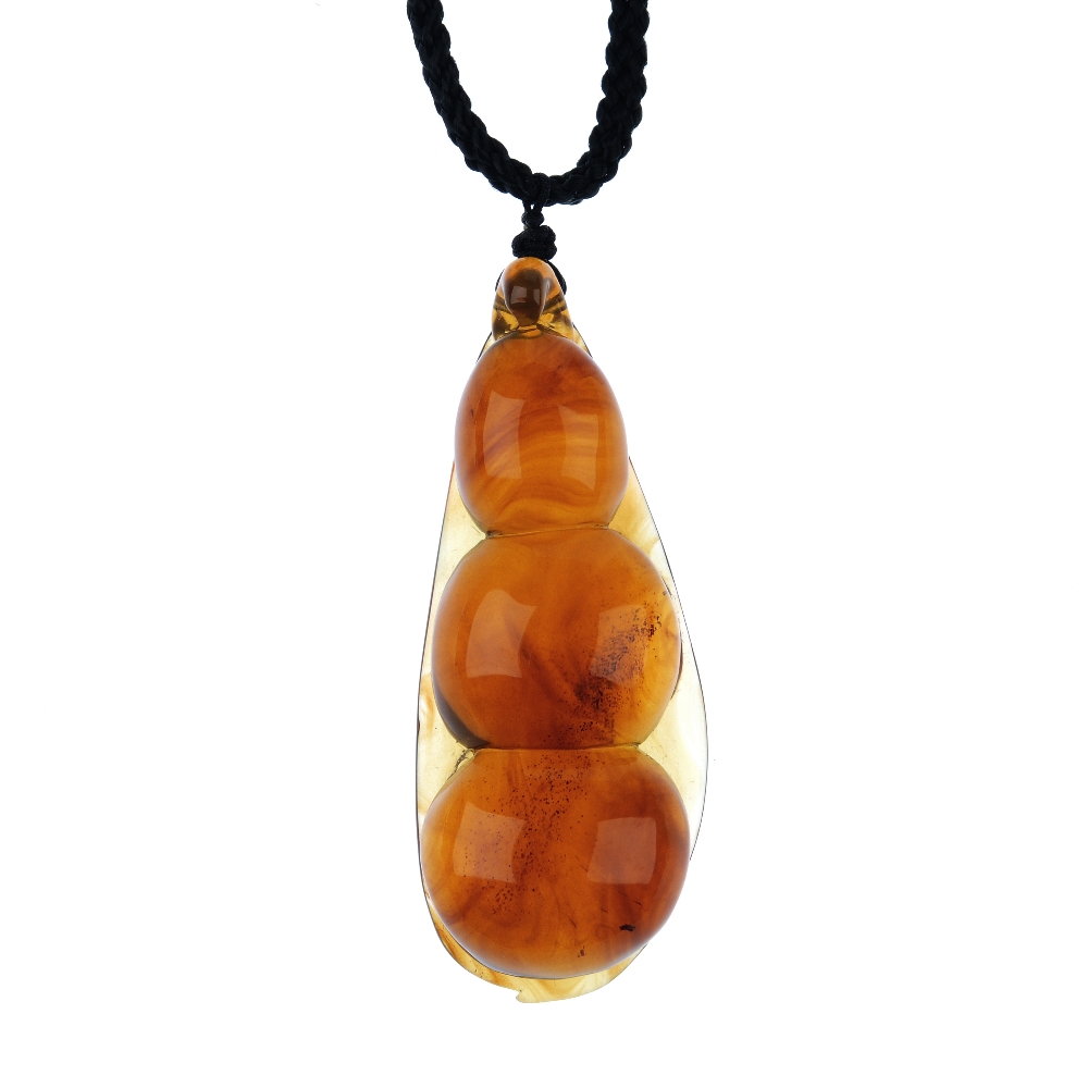 A natural Burmese amber pendant carved as a pea pod. The plaited black cord suspending the pear-