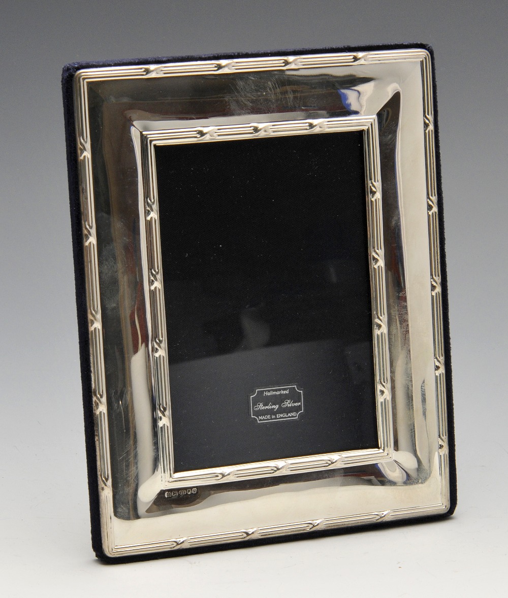 A modern silver mounted photograph frame of oblong form with reed and ribbon border and easel