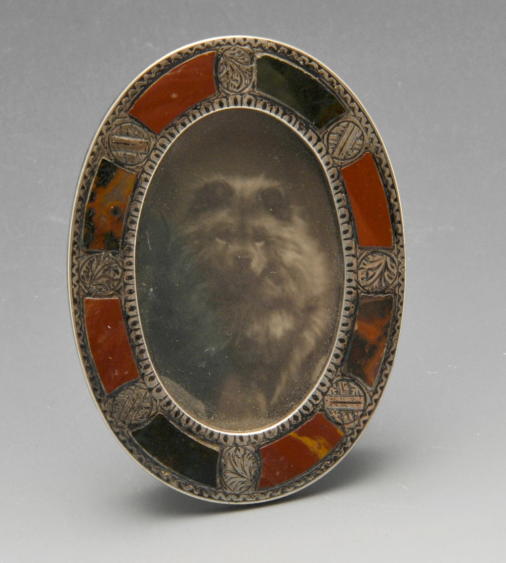 A late Victorian miniature silver photograph frame, the oval form inlaid with hardstones and